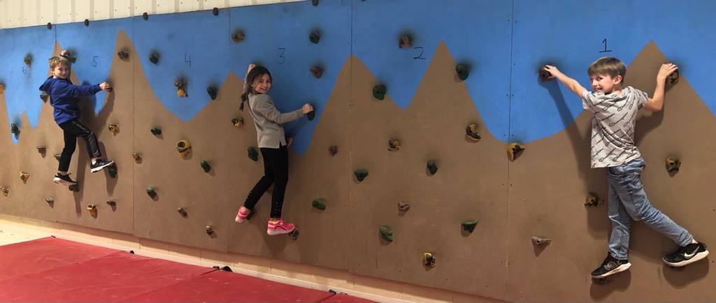 female student climbing a rock climbing wall